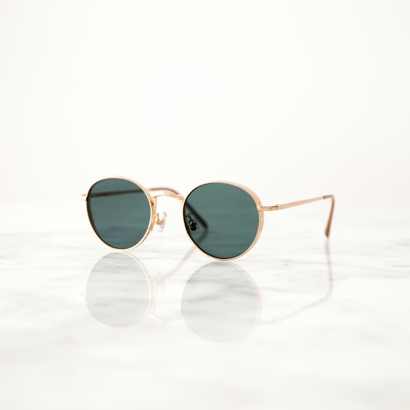 Round gold-frame sunglasses on marble